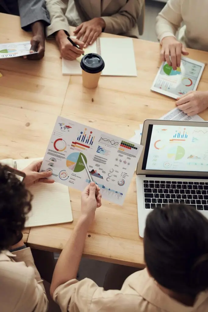 "Team of consultants analyzing an Excel dashboard with charts and graphs, one pointing at performance metrics"