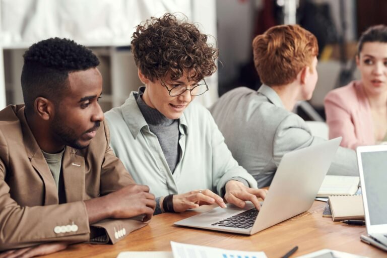 Team of Excel consultants collaborating at a desk to develop a financial modeling solution, including budgeting, forecasting, cash flow analysis, and investment returns.